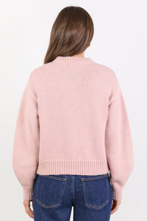 Person wearing a pink sweater and blue jeans on a white background