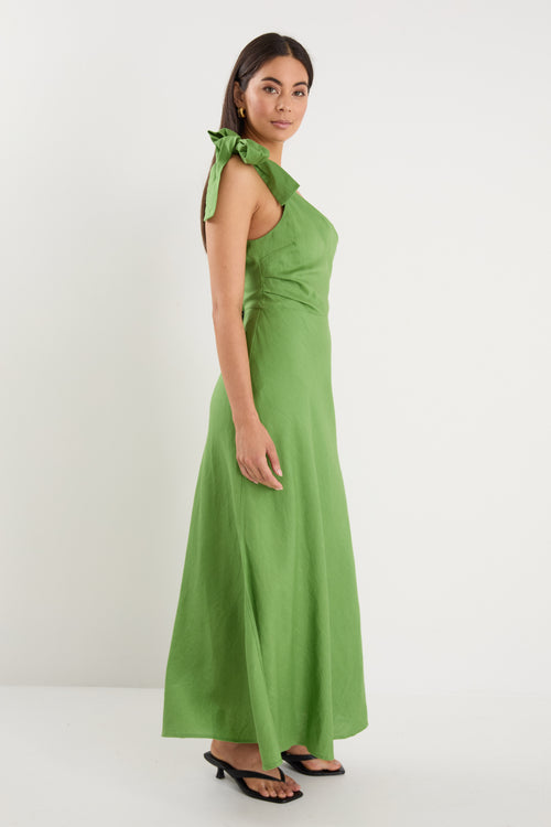 Model wears a one shoulder green midi dress with white heels
