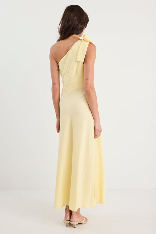 Woman wearing a light yellow one-shoulder dress on a white background