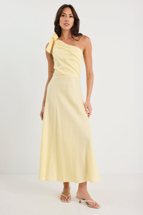 Woman wearing a light yellow one-shoulder dress on a white background