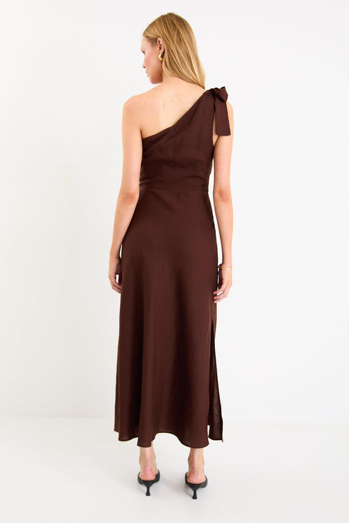 Model wearing a chocolate brown one-shoulder midi dress with a bow detail and a bias-cut skirt
