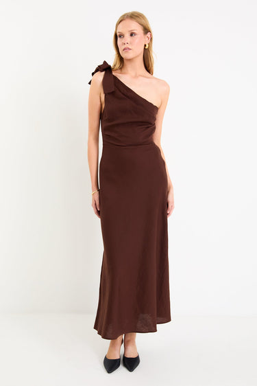 Model wearing a chocolate brown one-shoulder midi dress with a bow detail and a bias-cut skirt