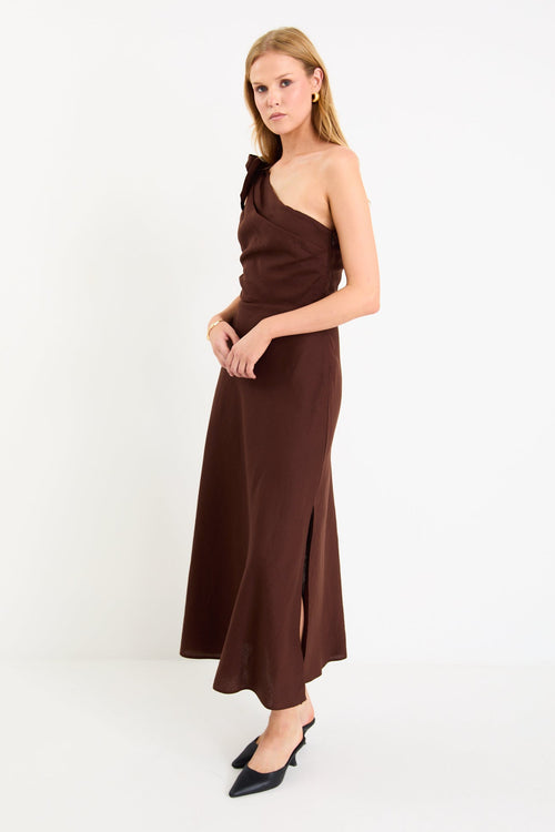 Model wearing a chocolate brown one-shoulder midi dress with a bow detail and a bias-cut skirt
