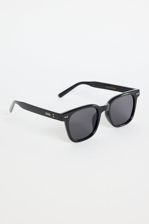 Glossy black classic square sunglasses with dark tinted lenses and subtle metal detailing, photographed on a white background.