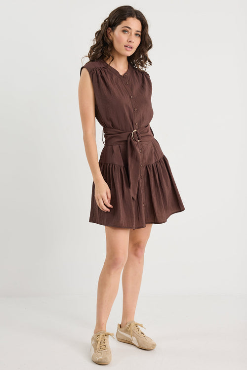 Woman wearing a brown dress with a belt on a white background