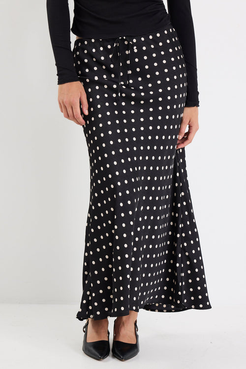 Person wearing a black and white polka dot skirt on a white background