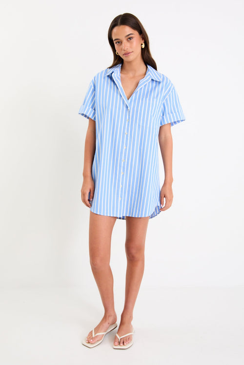 Model wearing a blue and white striped short sleeve mini shirt dress with a button front and collar.
