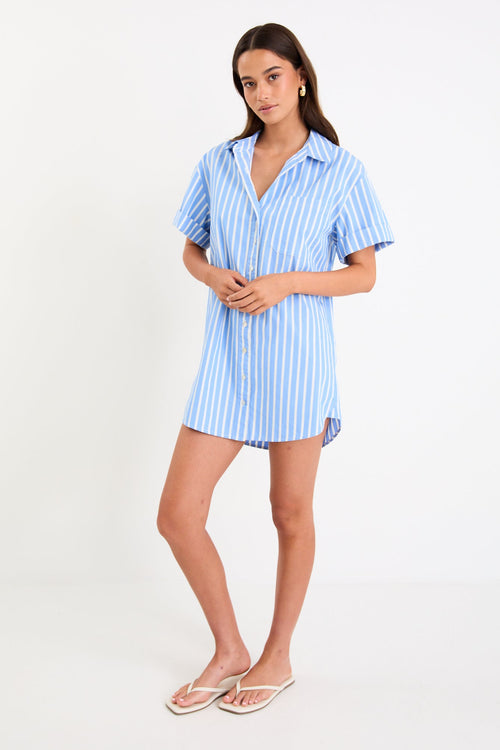 Model wearing a blue and white striped short sleeve mini shirt dress with a button front and collar.