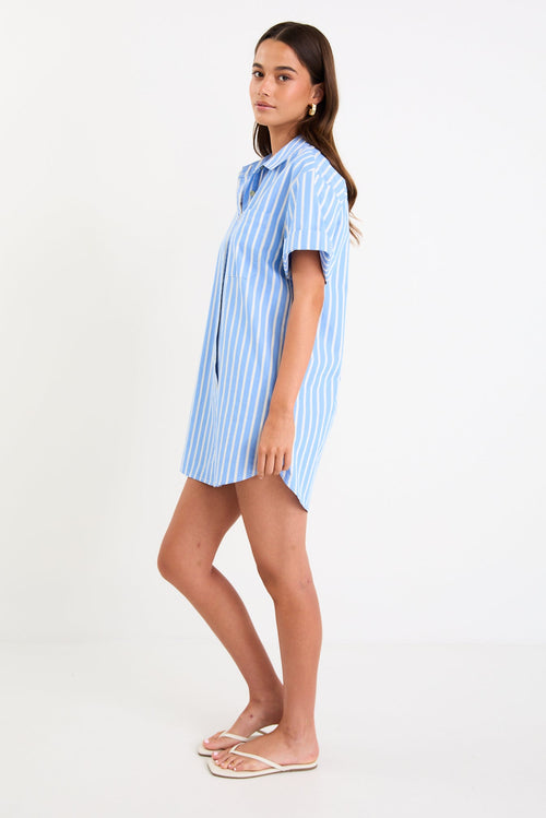 Model wearing a blue and white striped short sleeve mini shirt dress with a button front and collar.