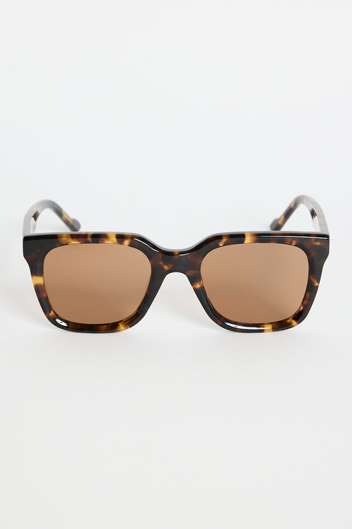 Rounded-square tortoiseshell sunglasses with warm brown tinted lenses, photographed on a white background