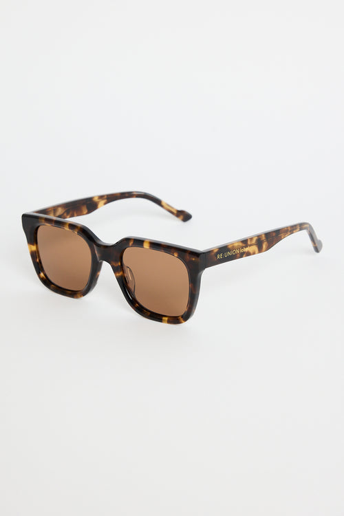 Rounded-square tortoiseshell sunglasses with warm brown tinted lenses, photographed on a white background