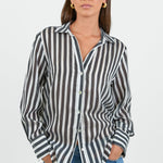 Woman wearing a black and white striped shirt with blue jeans on a white background