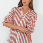 Woman wearing a striped shirt and jeans against a white background
