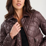 Woman wearing a quilted brown jacket against a white background
