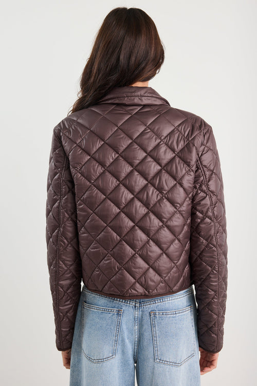 Person wearing a brown quilted jacket on a white background