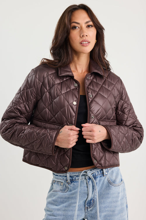 Woman wearing a quilted jacket and jeans on a white background