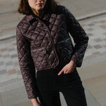 Woman wearing a quilted jacket standing on a stone pavement