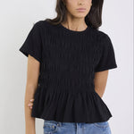 Woman wearing a black ruffled top and blue jeans on a white background