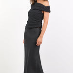 Person wearing a black off-shoulder top and long skirt on a white background