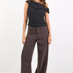 Woman wearing a black top and brown pants on a white background