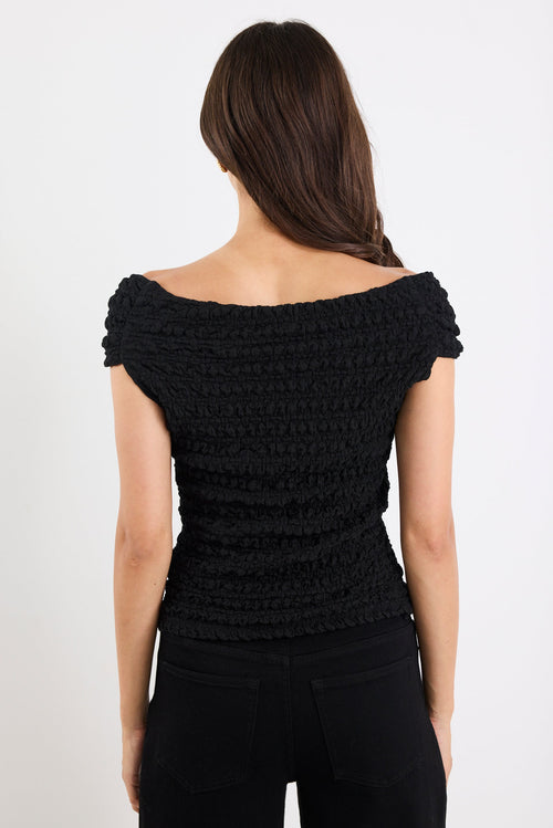 Woman wearing a black textured top on a white background
@col_pattern
