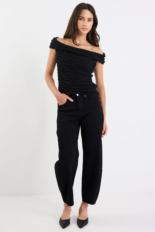 Woman wearing a black off-shoulder top and black pants on a white background