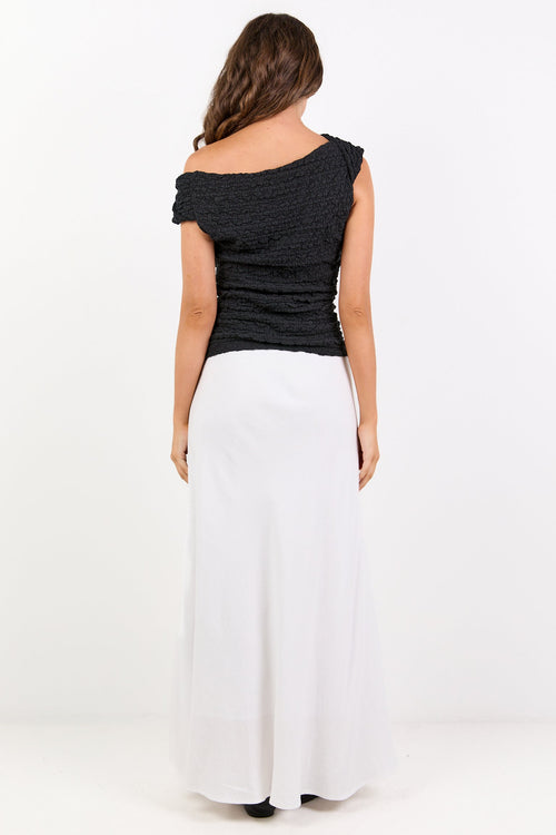 Woman wearing a black top and white pants on a white background