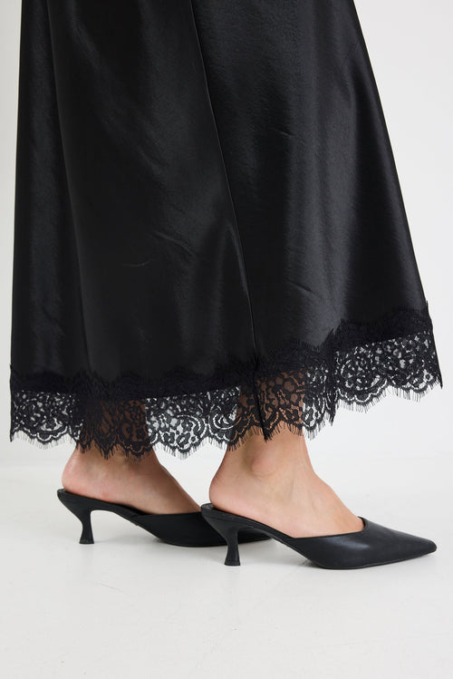 Black lace-trimmed pants with black high-heeled shoes on a white background