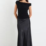 Woman wearing a black off-shoulder top and black skirt on a white background