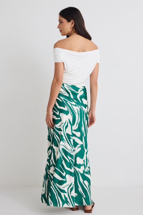 model wears off the shoulder white top and a green zebra print satin skirt