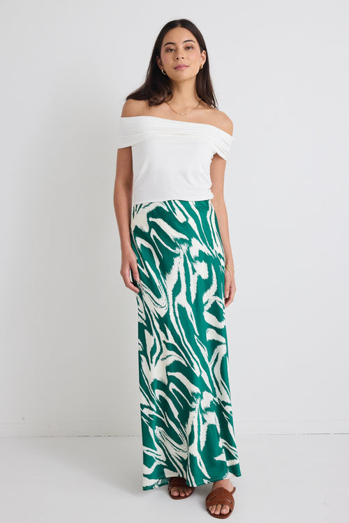 model wears off the shoulder white top and a green zebra print satin skirt