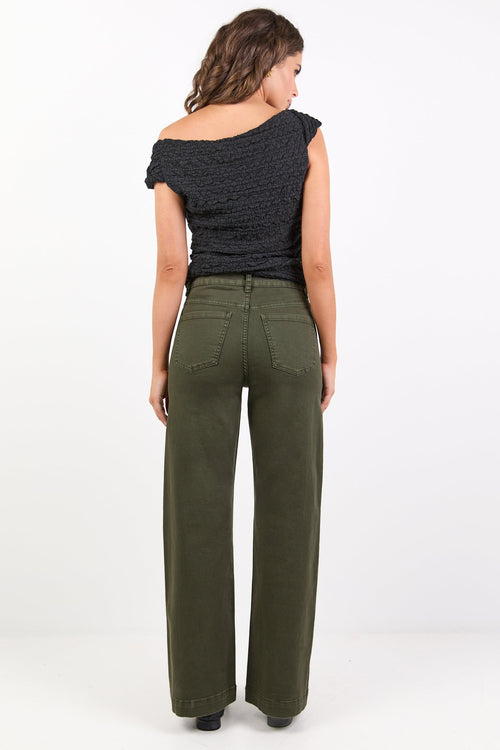 Woman wearing a black top and green pants on a white background