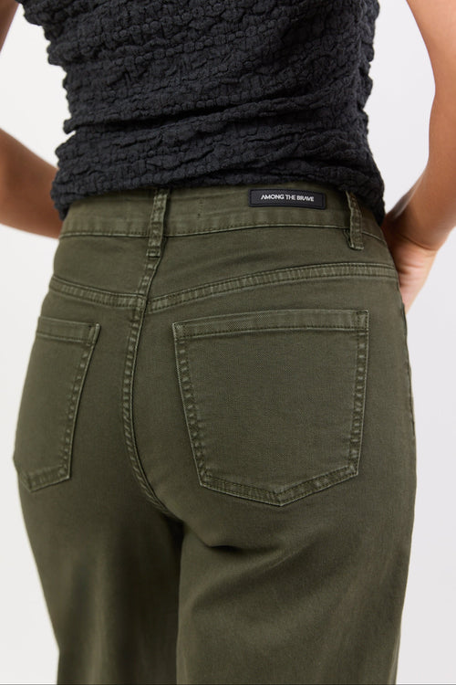 Person wearing green pants with a visible brand label on a white background