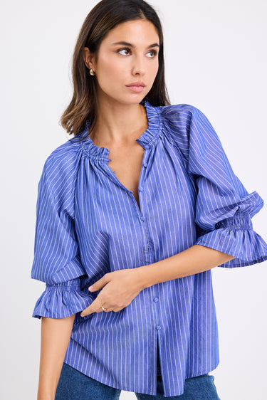 model wears a blue and white stripe shirt with dark blue jeans