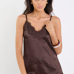 Woman wearing a brown lace-trimmed top and blue jeans on a white background