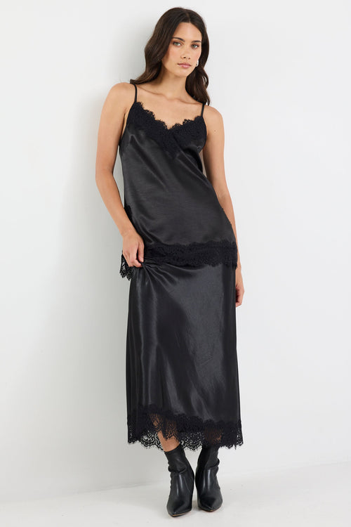 Woman wearing a black satin slip dress on a white background