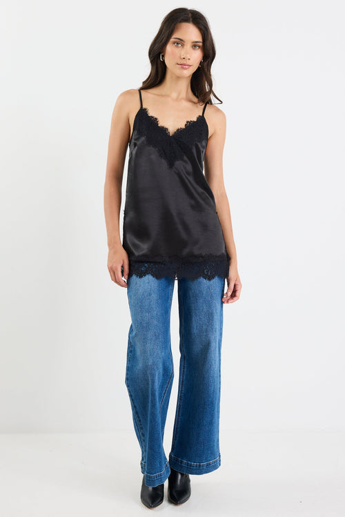 Woman wearing a black lace top and blue jeans on a white background