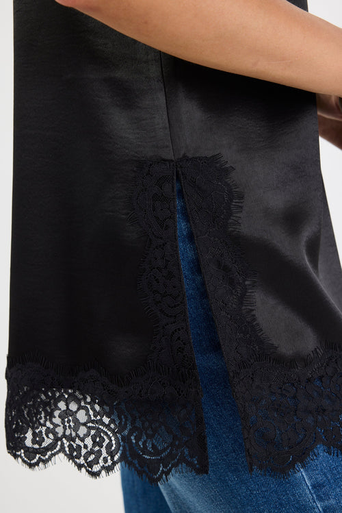 Black lace-trimmed top worn by a person on a white background