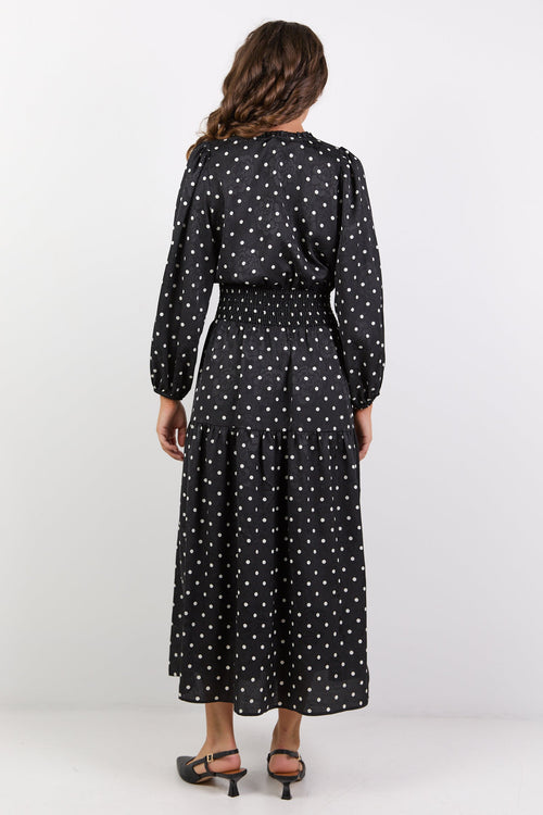 Woman wearing a black polka dot dress on a white background