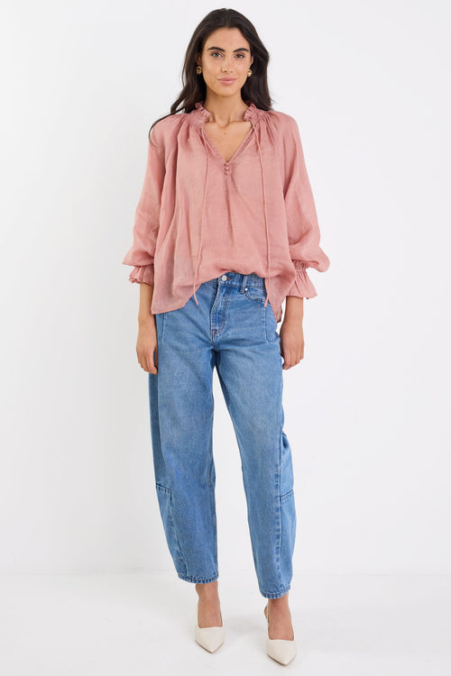Woman wearing a pink blouse and blue jeans on a white background