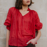 Woman wearing a red blouse against a beige wall