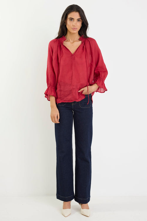 Woman wearing a red blouse and dark blue jeans on a white background