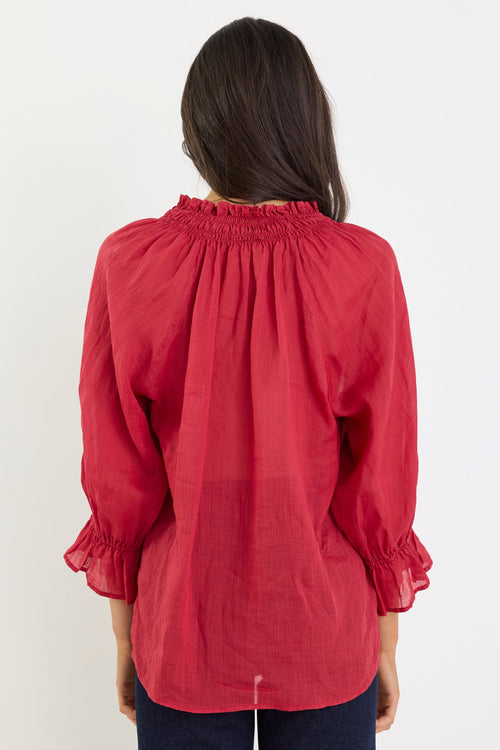 Person wearing a red blouse with long sleeves on a white background