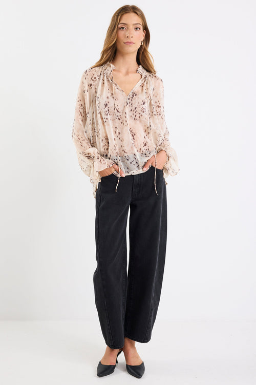 Woman wearing a floral blouse and black pants on a white background