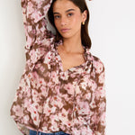 Woman wearing a floral blouse and jeans against a white background