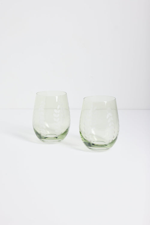 Two clear stemless wine glasses with a subtle etched pattern, standing side-by-side on a white surface against a white background.