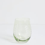 A clear stemless wine glass with a textured, dimpled pattern on a white studio background.