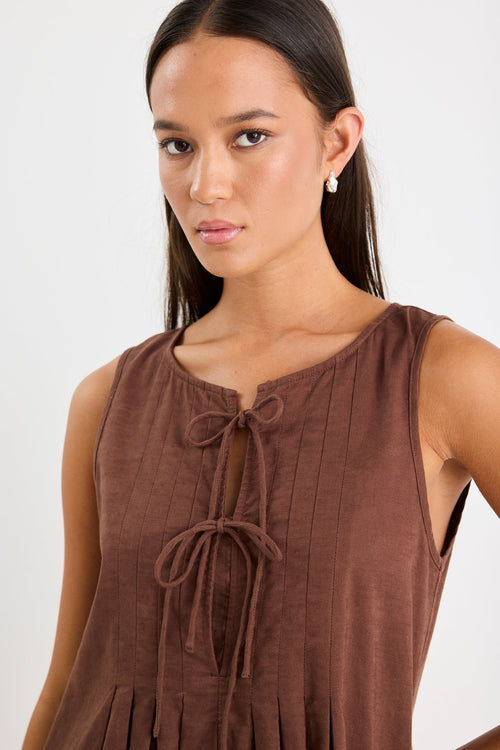 Woman wearing a brown mini dress with tie front and pleating
