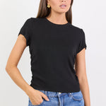 Woman wearing a black t-shirt and blue jeans against a white background