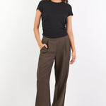 Woman wearing a black t-shirt and brown wide-leg pants on a white background
